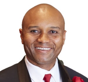 A headshot style photo of a man smiling towards you.